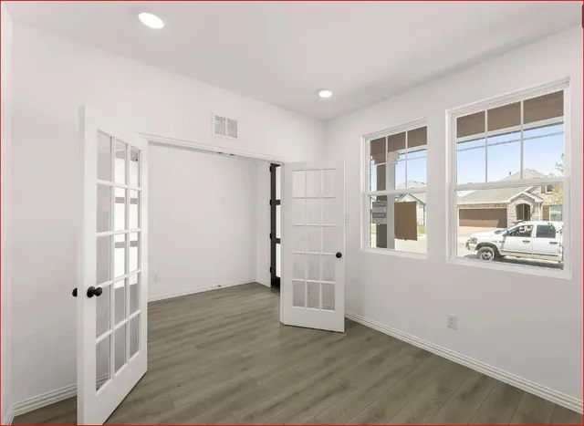 a view of an empty room with wooden floor and a window