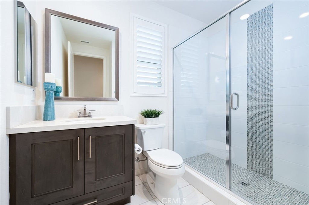 126 Brambles Irvine, CA 92618 - Photo 25 of 59 a bathroom with a toilet a sink a glass door a shower and a mirror