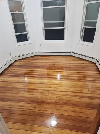a view of an empty room with wooden floor and cabinet