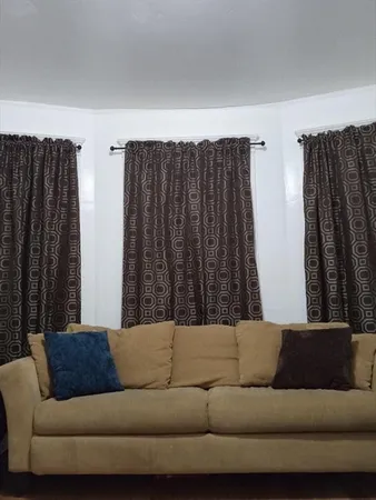 a living room with a couch and a kitchen view