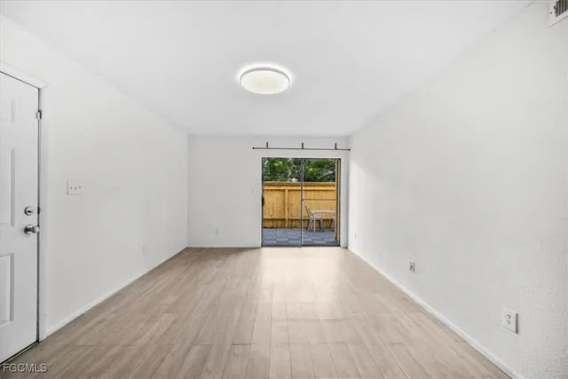 an empty room with a window and wooden floor