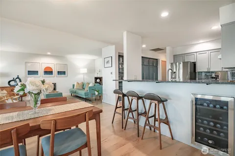 a kitchen with stainless steel appliances kitchen island granite countertop a table chairs and a refrigerator
