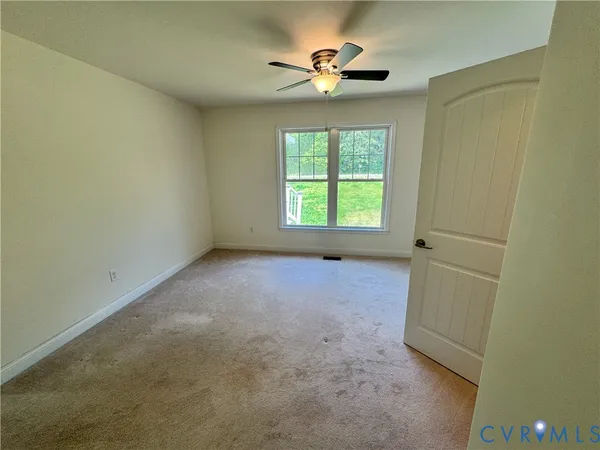 an empty room with a window and a fan