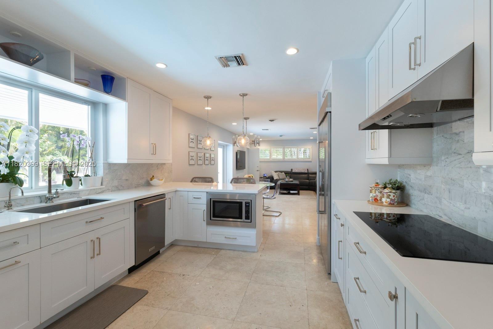11900 Southwest 72nd Place Pinecrest, FL 33156 - Photo 11 of 37 a large white kitchen with a large window a sink and white stainless steel appliances