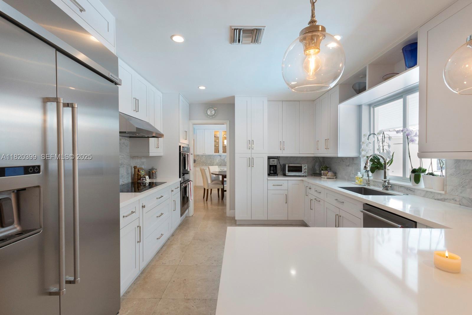 11900 Southwest 72nd Place Pinecrest, FL 33156 - Photo 12 of 37 a large kitchen with stainless steel appliances kitchen island granite countertop a refrigerator and a sink
