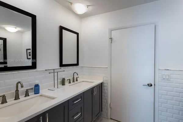 a bathroom with double sink and two mirror