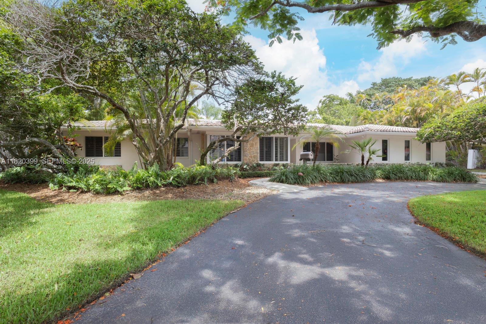11900 Southwest 72nd Place Pinecrest, FL 33156 - Photo 3 of 37 a front view of a house with a yard and potted plants