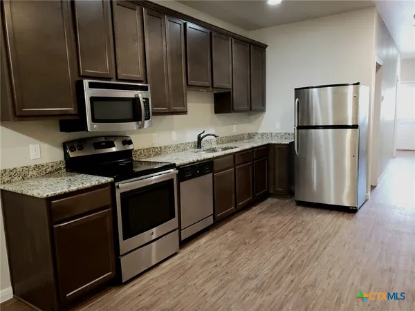 a kitchen with stainless steel appliances granite countertop a stove a refrigerator and a microwave
