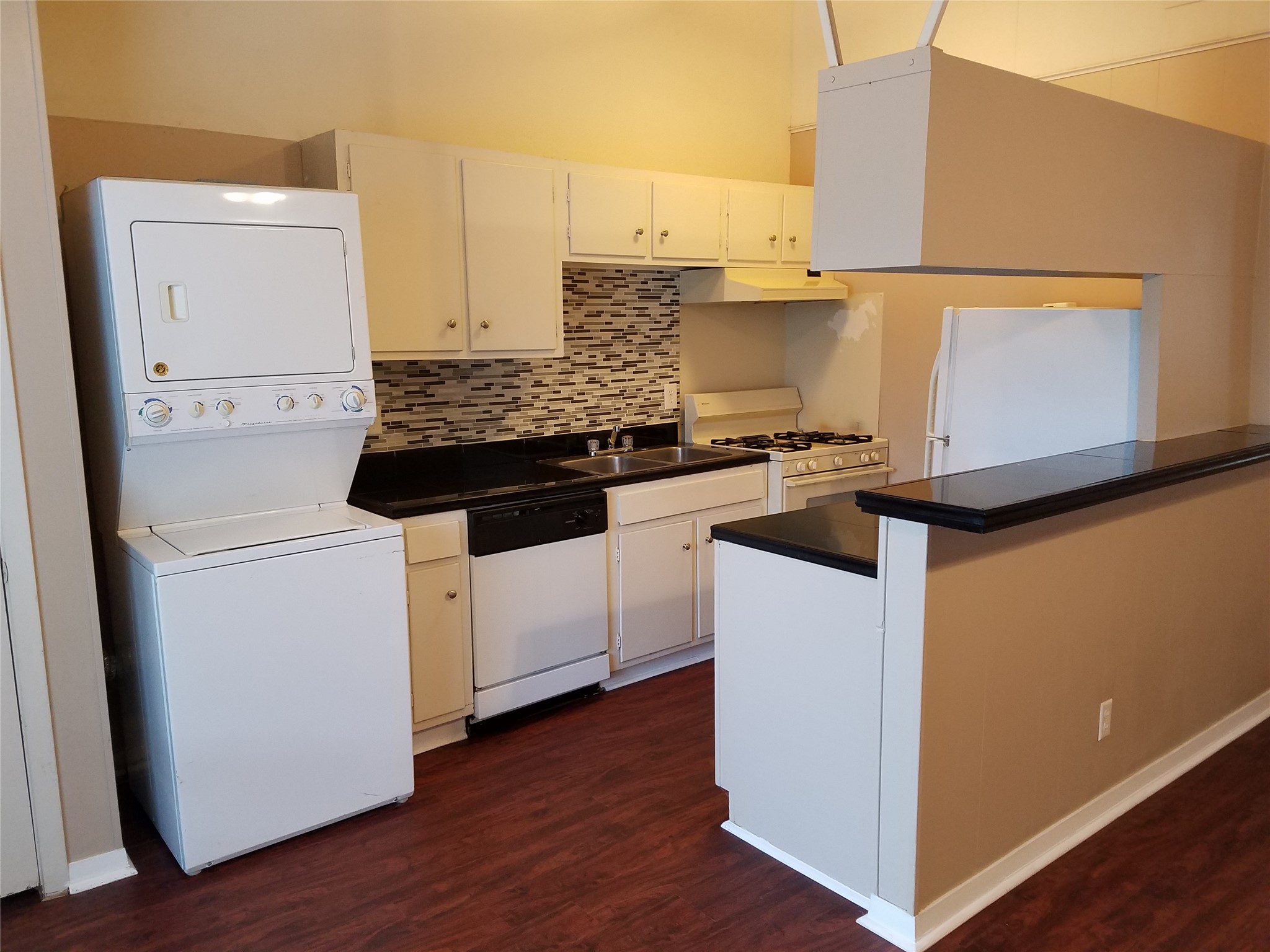 606 West 51st Street, Unit 104 Austin, TX 78751 - Photo 3 of 21 Kitchen with dark countertops, white appliances, backsplash, and dark wood-style floors