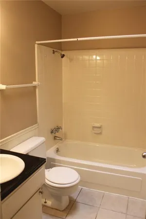 a bathroom with a granite countertop bathtub shower sink vanity and toilet