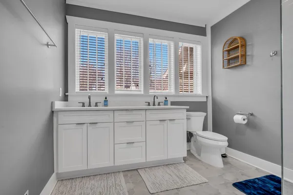 a bathroom with a granite countertop sink a toilet and a window
