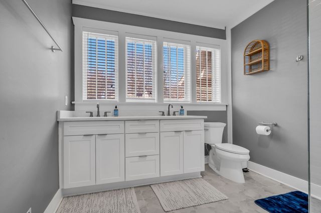 a bathroom with a granite countertop sink a toilet and a window