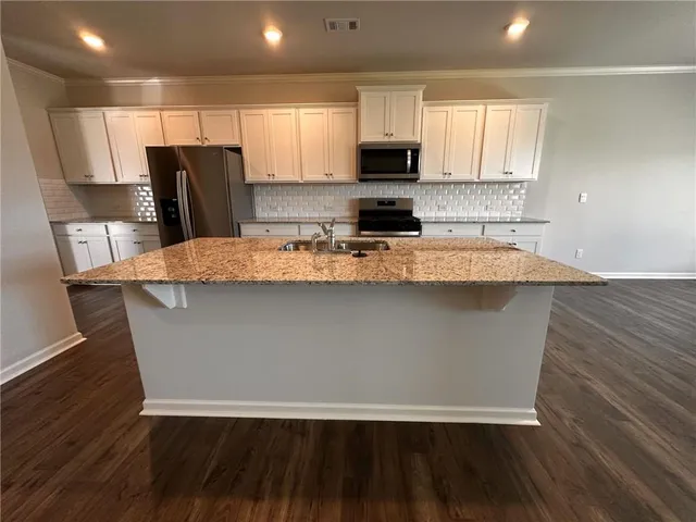 a view of kitchen with granite countertop stainless steel appliances a refrigerator microwave and sink
