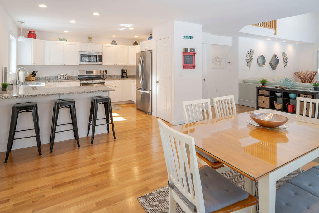 45 Perch Pond Way Wellfleet, MA 02667 - Photo 26 of 82 a kitchen with stainless steel appliances granite countertop a stove a refrigerator a microwave and a dining table with wooden floor