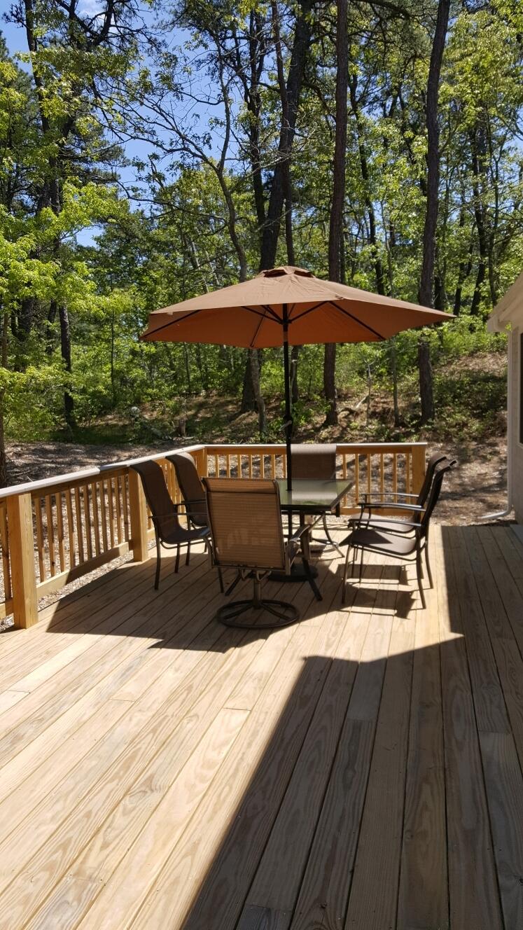 45 Perch Pond Way Wellfleet, MA 02667 - Photo 72 of 82 a view of a roof deck with table and chairs under an umbrella with wooden floor