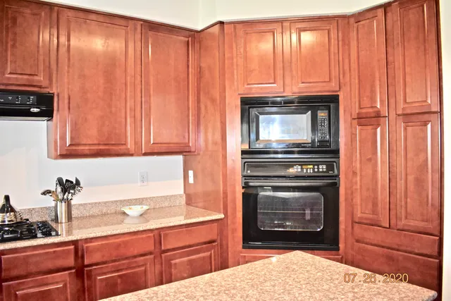 a kitchen with granite countertop wooden cabinets and a stove top oven