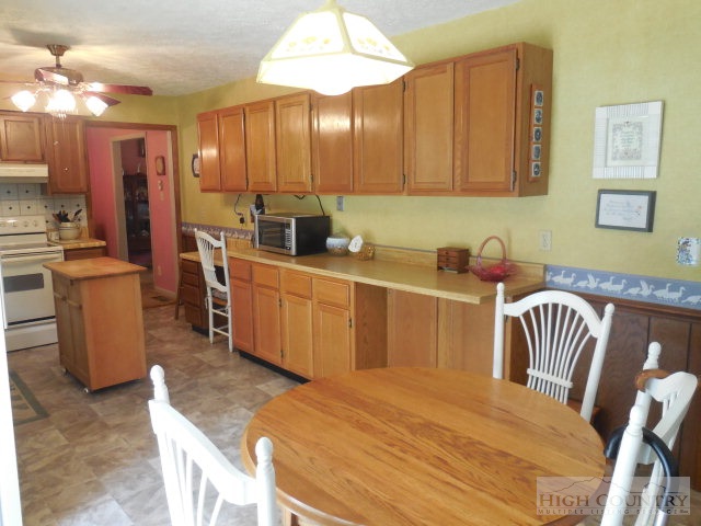1310 Ben Miller Road Deep Gap, NC 28618 - Photo 8 of 22 a kitchen with stainless steel appliances kitchen island granite countertop a table chairs in it and a wooden floors
