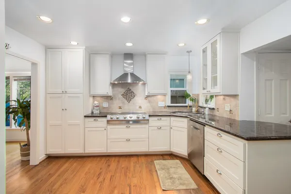 a large kitchen with stainless steel appliances granite countertop a stove a sink and white cabinets