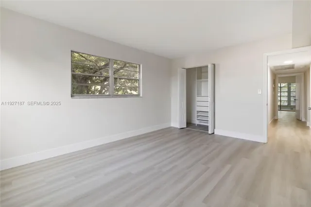 a view of an empty room with wooden floor and closet