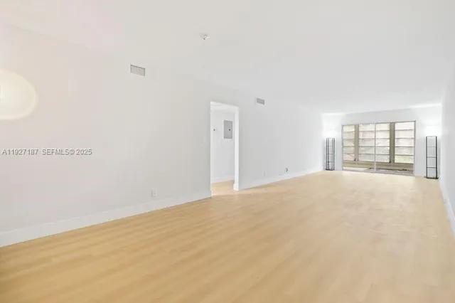 a view of an empty room with wooden floor and entryway