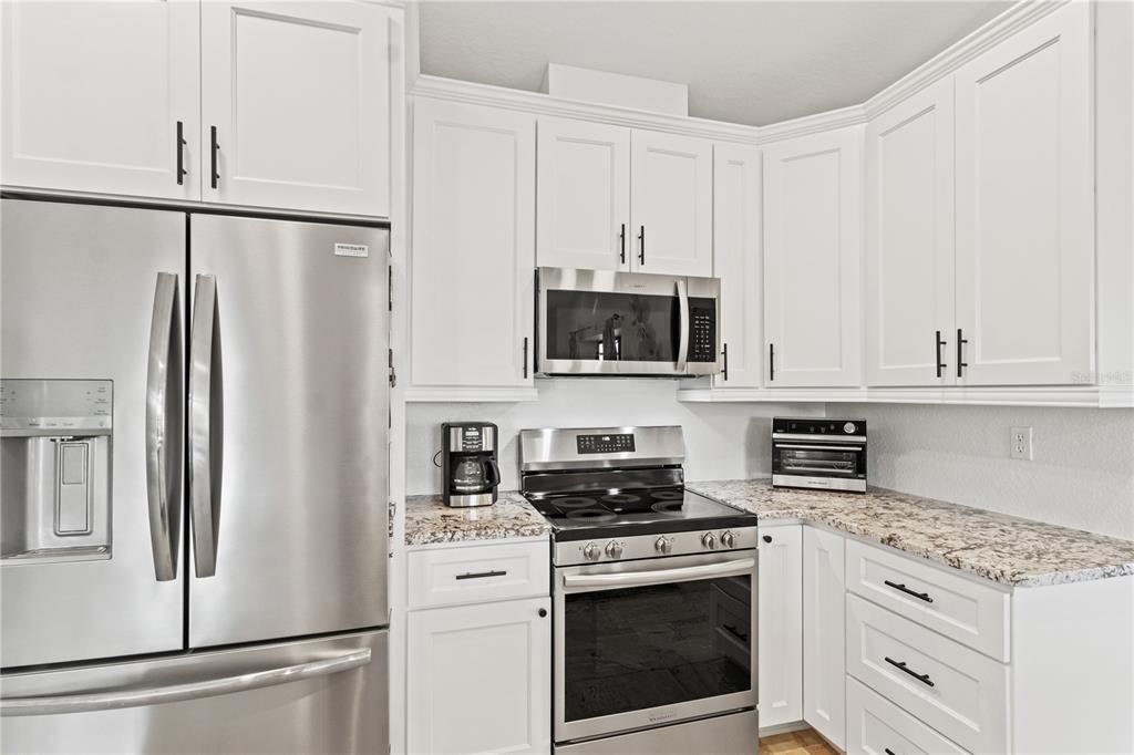 488 Fieldstone Lane Spring Hill, FL 34606 - Photo 19 of 55 a kitchen with stainless steel appliances white cabinets white stove a refrigerator and a granite counter tops