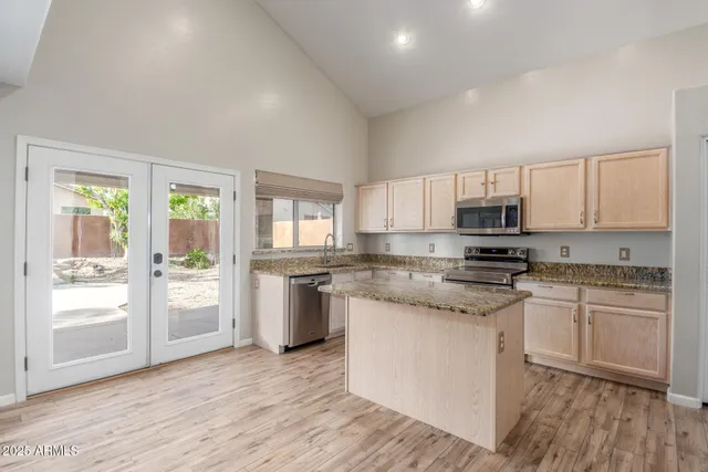 a kitchen with stainless steel appliances granite countertop a stove top oven a sink dishwasher a refrigerator and white cabinets with wooden floor
