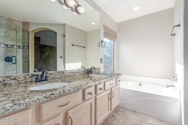 a bathroom with a granite countertop sink mirror and a bath tub
