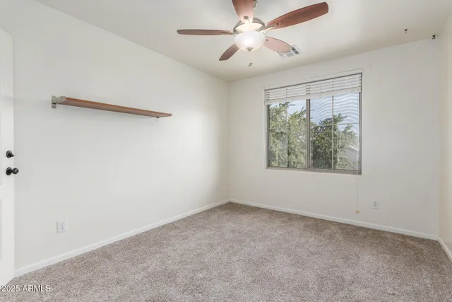 an empty room with a window and a fan