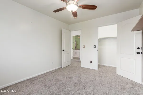 an empty room with chandelier fan and windows