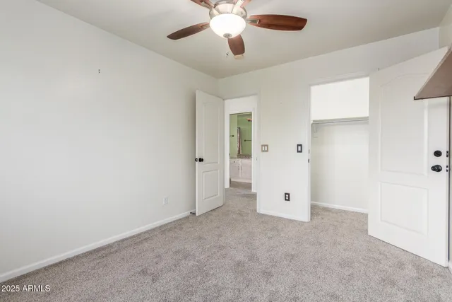 an empty room with chandelier fan and windows