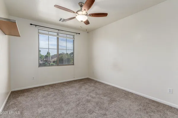 an empty room with a window and a fan
