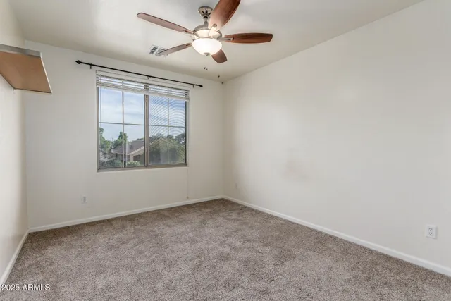 an empty room with a window and a fan