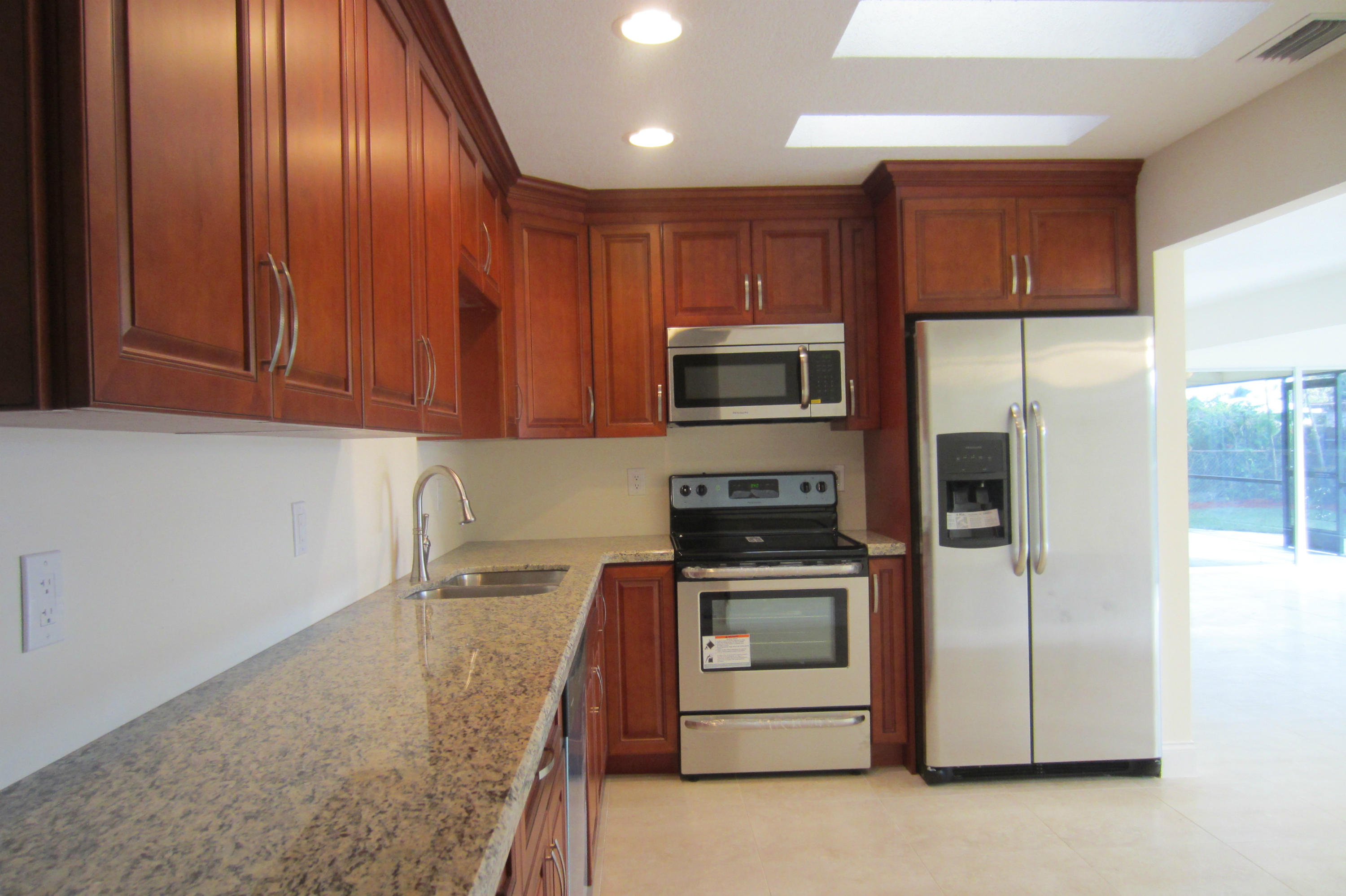 310 Northeast 23rd Way Boca Raton, FL 33431 - Photo 2 of 16 a kitchen with stainless steel appliances granite countertop a refrigerator a stove and a sink with wooden cabinets