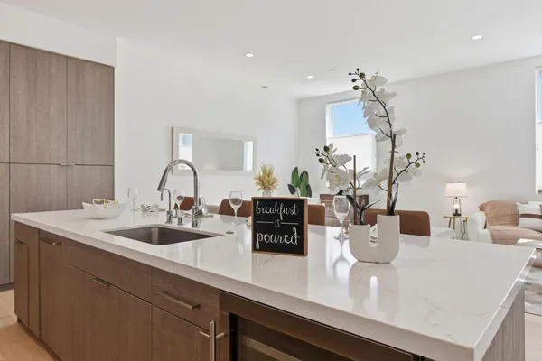 a living room with stainless steel appliances kitchen island granite countertop a dining table chairs and a refrigerator