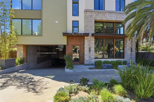 a view of a brick house with plants and large tree