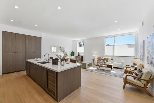 a room with stainless steel appliances kitchen island granite countertop a sink and white cabinets with wooden floor