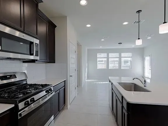 a kitchen with stainless steel appliances a sink a stove a refrigerator and cabinets