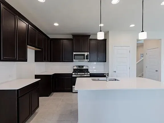 a kitchen with stainless steel appliances kitchen island granite countertop a stove and a sink