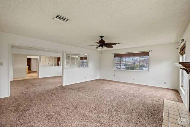 an empty room with windows and ceiling fan