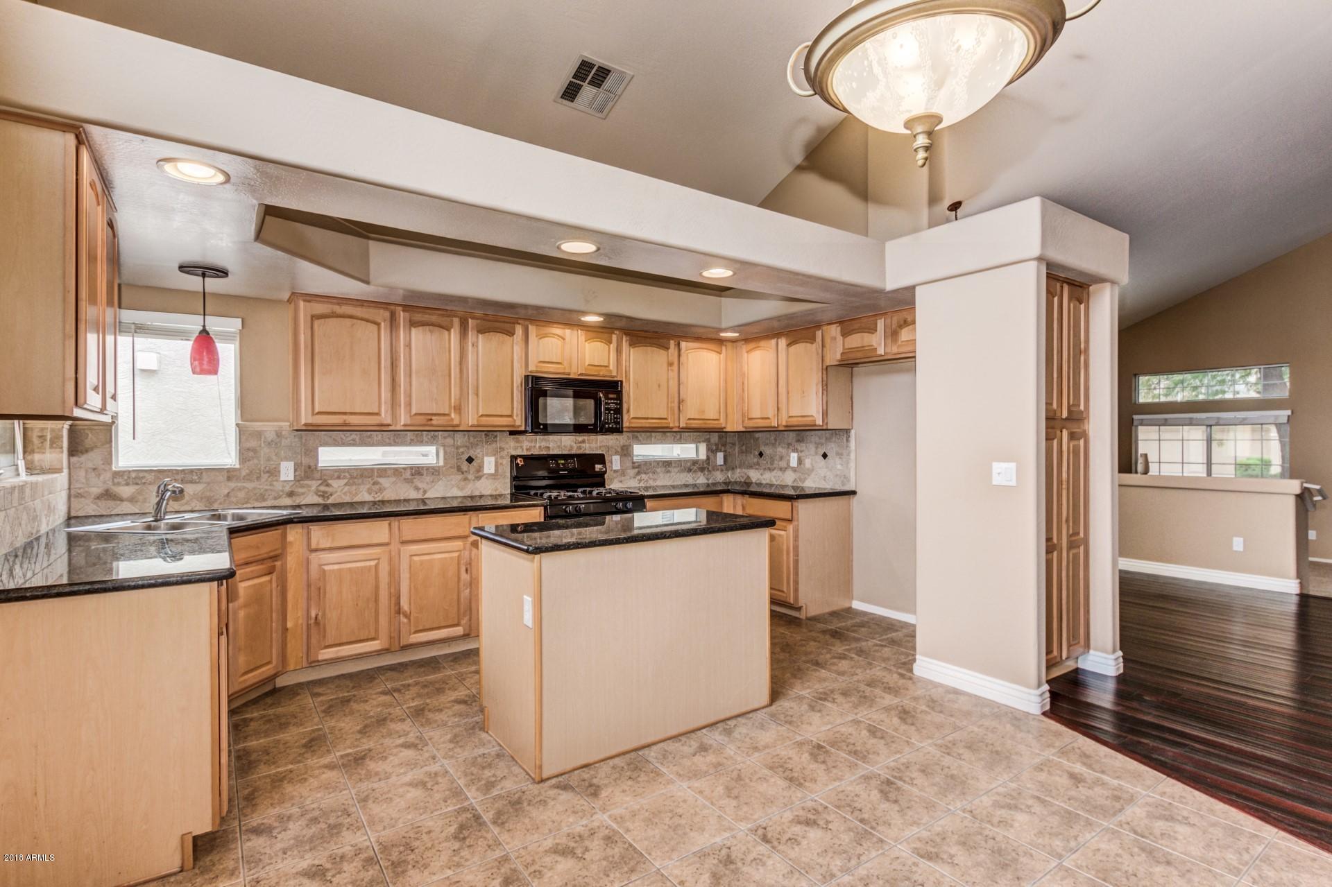 15770 West Calavar Road Surprise, AZ 85379 - Photo 3 of 21 a kitchen with stainless steel appliances kitchen island granite countertop a stove cabinets and refrigerator