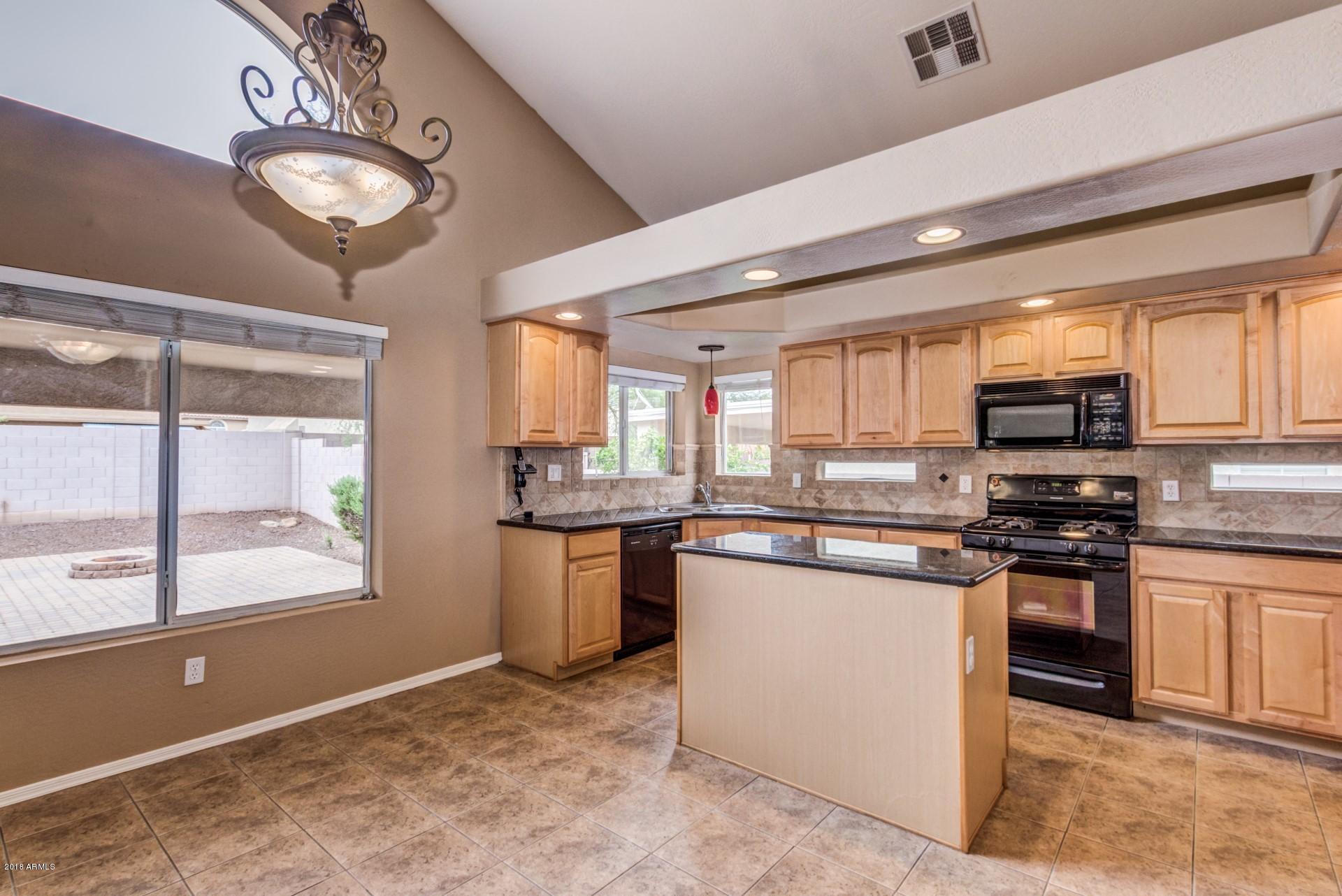 15770 West Calavar Road Surprise, AZ 85379 - Photo 7 of 21 a kitchen with stainless steel appliances granite countertop a stove a sink and a microwave