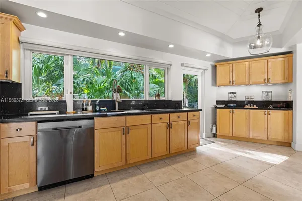 a kitchen with granite countertop white cabinets white appliances a sink and a large window