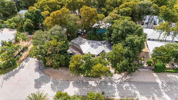 an aerial view of a house with a yard and trees all around