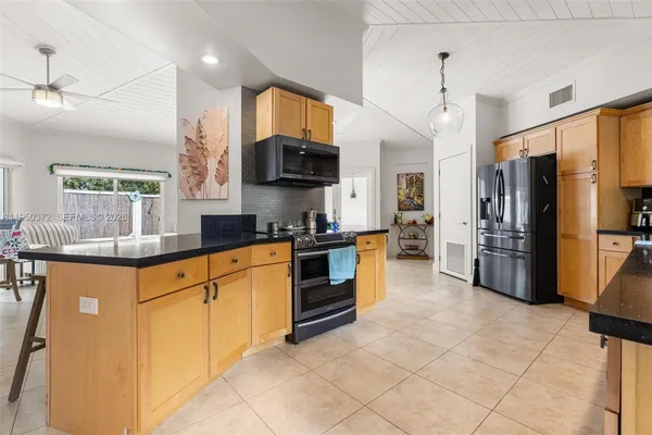 a kitchen with stainless steel appliances granite countertop a refrigerator a stove a sink a microwave and island