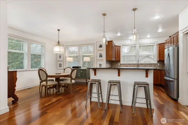 a view of a dining room and livingroom with furniture wooden floor a rug a chandelier and a mirror