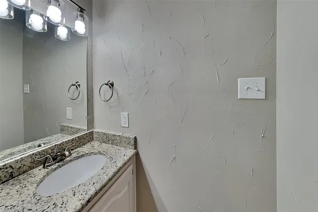 a bathroom with a granite countertop sink a large mirror and a shower
