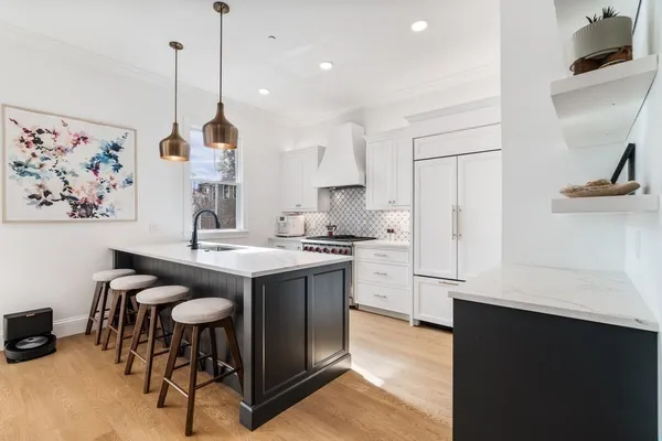 a kitchen with stainless steel appliances granite countertop a sink a stove a refrigerator and island with wooden floor