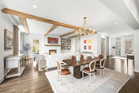 a large white kitchen with lots of counter space a sink appliances and living room view