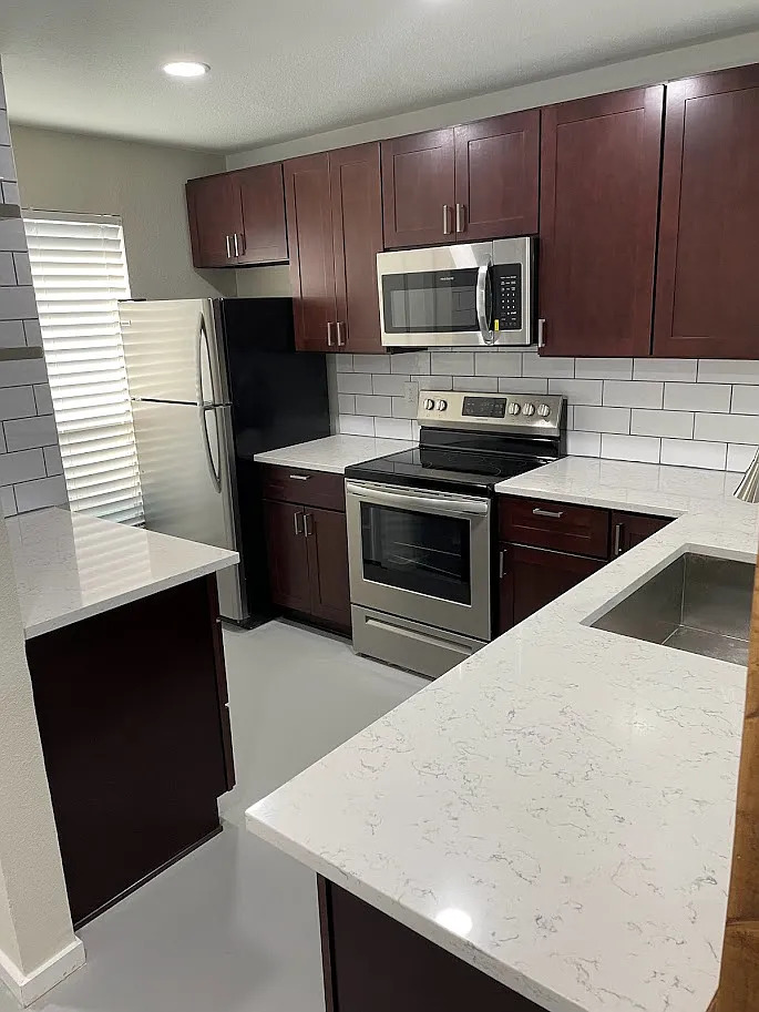 2018 West Rundberg Lane, Unit 16C Austin, TX 78758 - Photo 3 of 12 a kitchen with kitchen island granite countertop wooden cabinets and stainless steel appliances