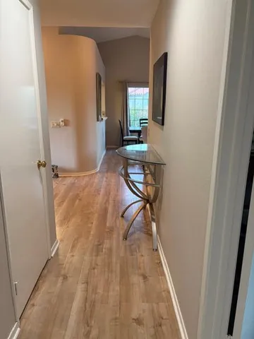 a view of a hallway with wooden floor and a bathroom